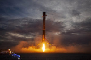 Model 3 near Falcon 9 booster landing vertically